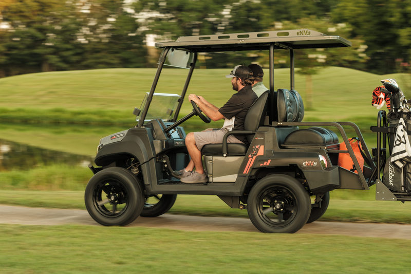 Side view of golfers driving envy through golf course